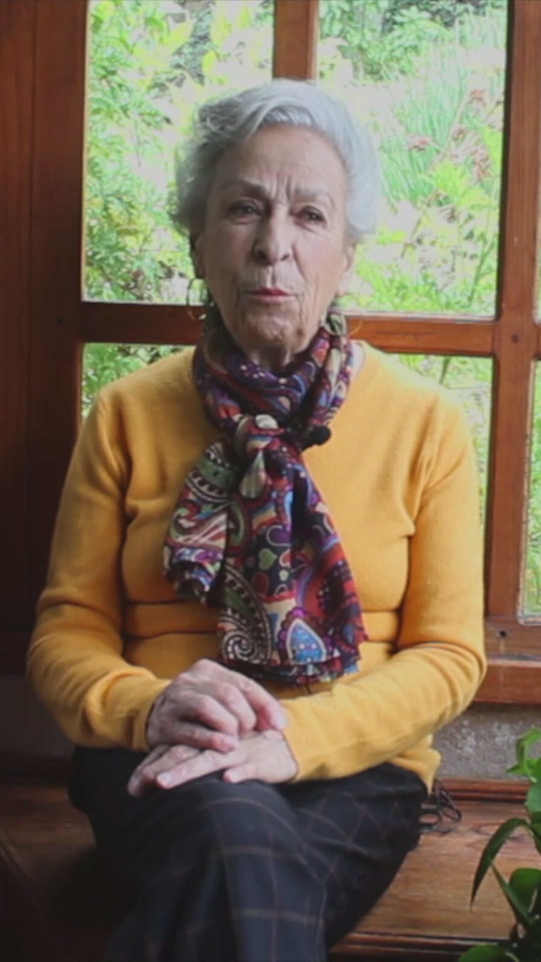 Cargar video: Video de una mujer mayor contando la historia tradicional y el origen artesanal del Rompope Carmelita, grabada en una ventana con fondo natural.